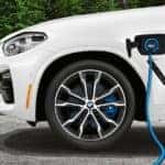 BMW X3e plug-in hybrid connected to a charger on the road.