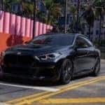 Dark BMW in an urban setting, driving to the stop light.
