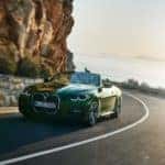 New BMW 4 Series convertible driving on a winding road near the ocean.