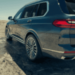 BMW X7 driving on a dirt road. Shot from the rear.