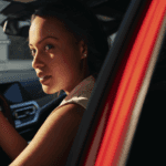 Young woman in a BMW, looking back over her shoulder.