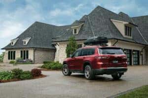 Red Grand Cherokee L sitting in front of a house
