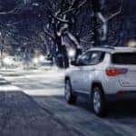 Jeep Compass driving down street in winter