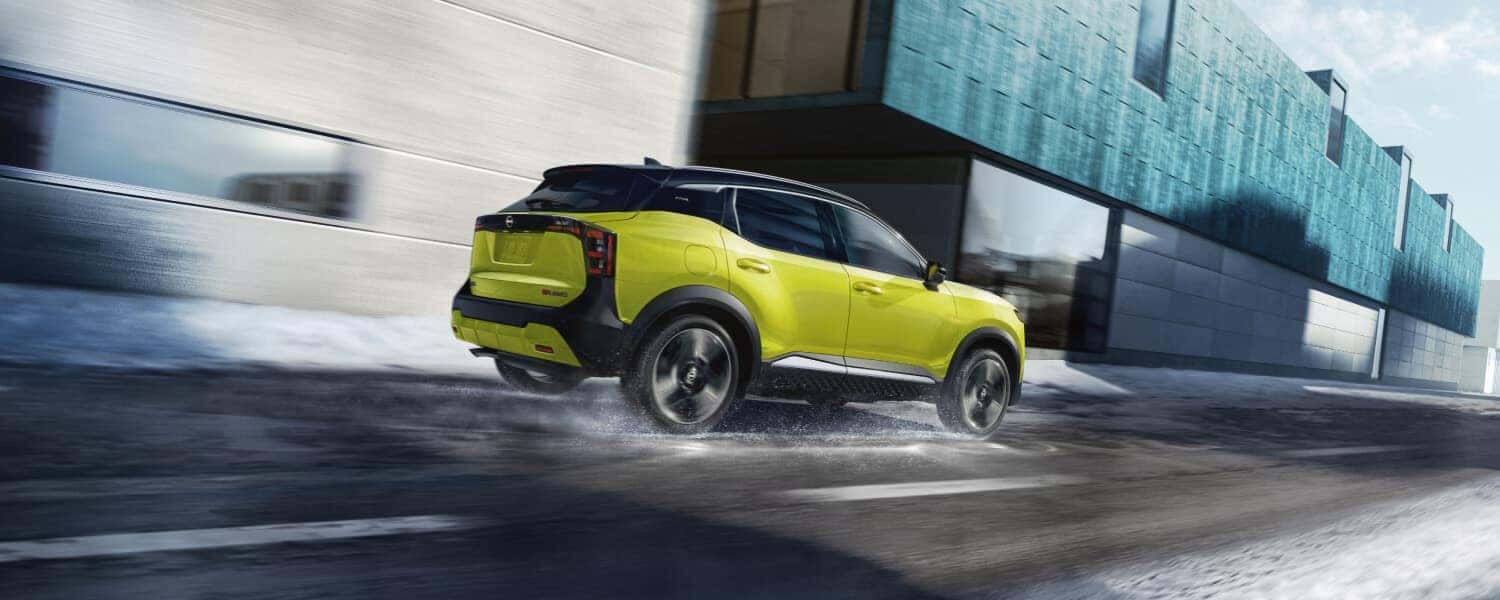 A yellow-green Nissan Kicks driving over a slightly snowy road