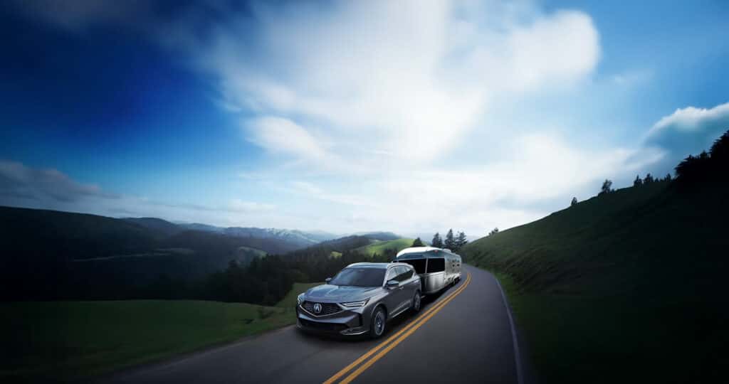 2026 Acura MDX towing a camper through the mountains