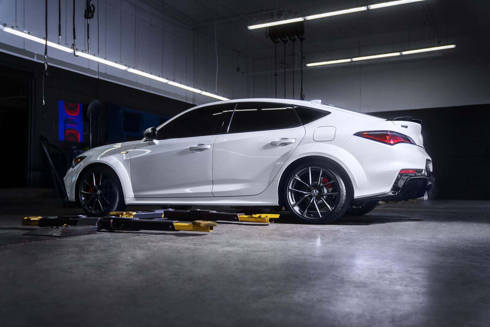 An Acura Integra Type S viewed from the side in a service bay, positioned over an open lift