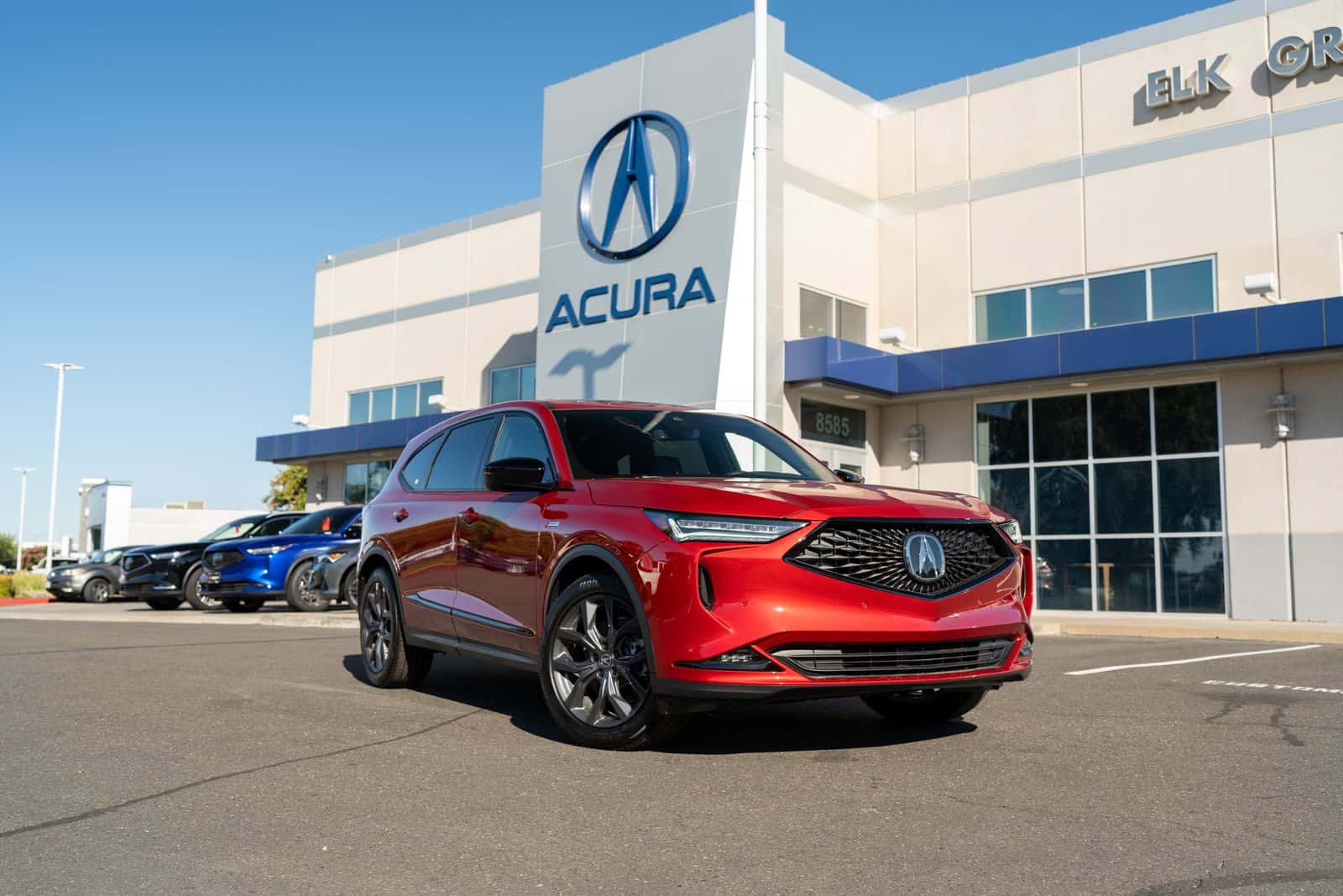 Red Acura MDX A-Spec parked outside the Elk Grove Acura showroom entrance