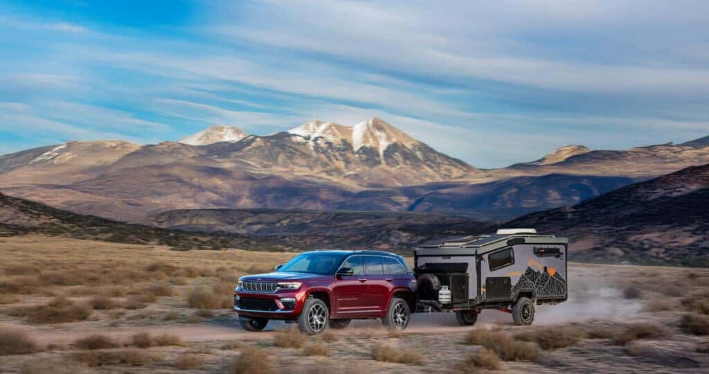 2025 Jeep Grand Cherokee towing capacity shown pulling a Boreas Camper down gravel road