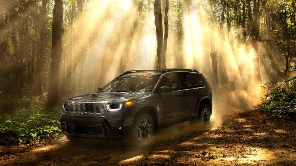 2026 Jeep Cherokee trim driving through forest with sun rays shinning through