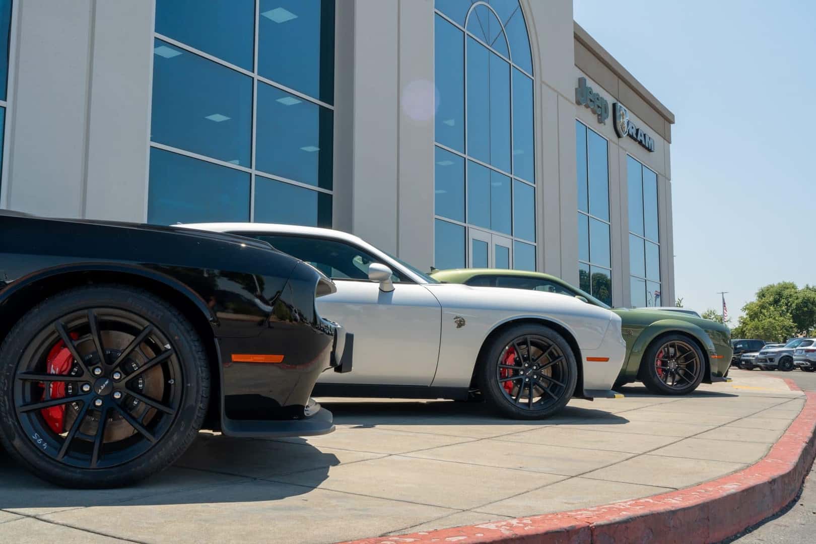 Red brake calipers behind the black wheels of Dodge Challenger models parked outside Elk Grove Dodge Chrysler Jeep Ram