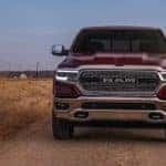 A red 2019 Ram truck on a dusty dirt road with a barbed wire fence