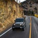 A black 2019 Jeep Wrangler driving along a cliffside
