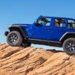 A blue 2020 Jeep Wrangler Rubicon is parked on a large rock after leaving a Jeep dealership in Ennis, TX.