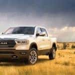 Look for this truck at a Ram dealer near you, a white 2020 Ram 1500 is parked in a field near Ennis, TX, and is next to a windmill.