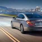 Gray Honda Accord driving on highway with city skyline in background
