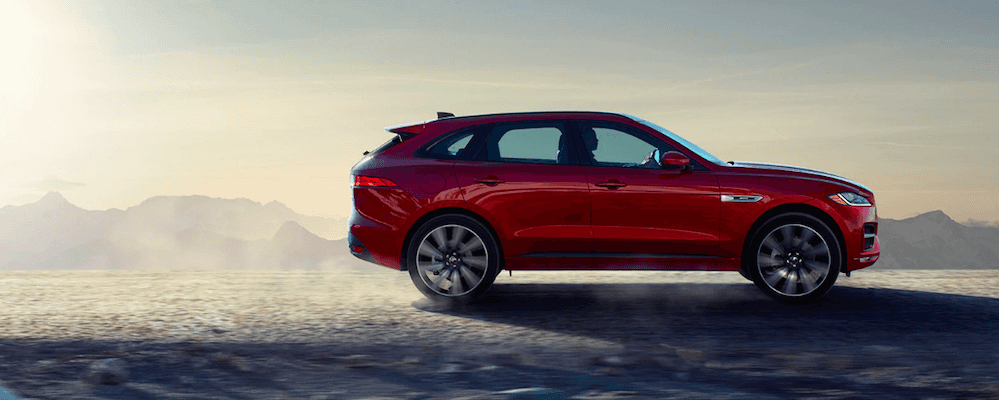 Profile of red 2020 Jaguar F-PACE driving on icy road