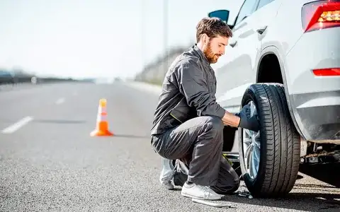 Driver learning how to change a flat tire safely on the roadside using a car jack