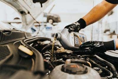 Mechanic pouring oil into motor car engine