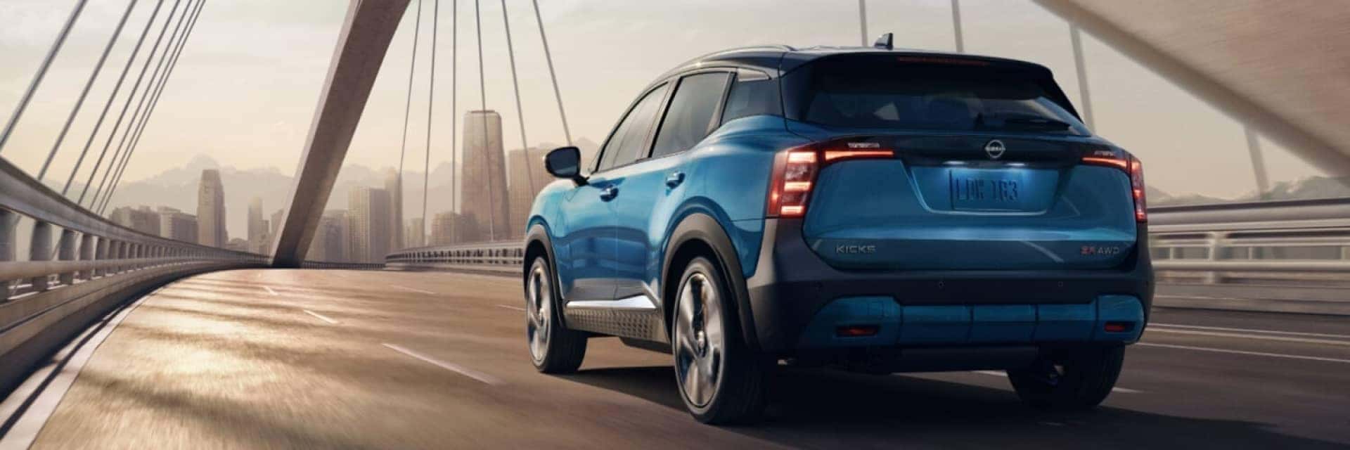 Blue 2025 Nissan Kicks driving over a cable bridge