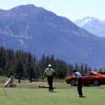 Three people golfing with a classic Ferrari in the background