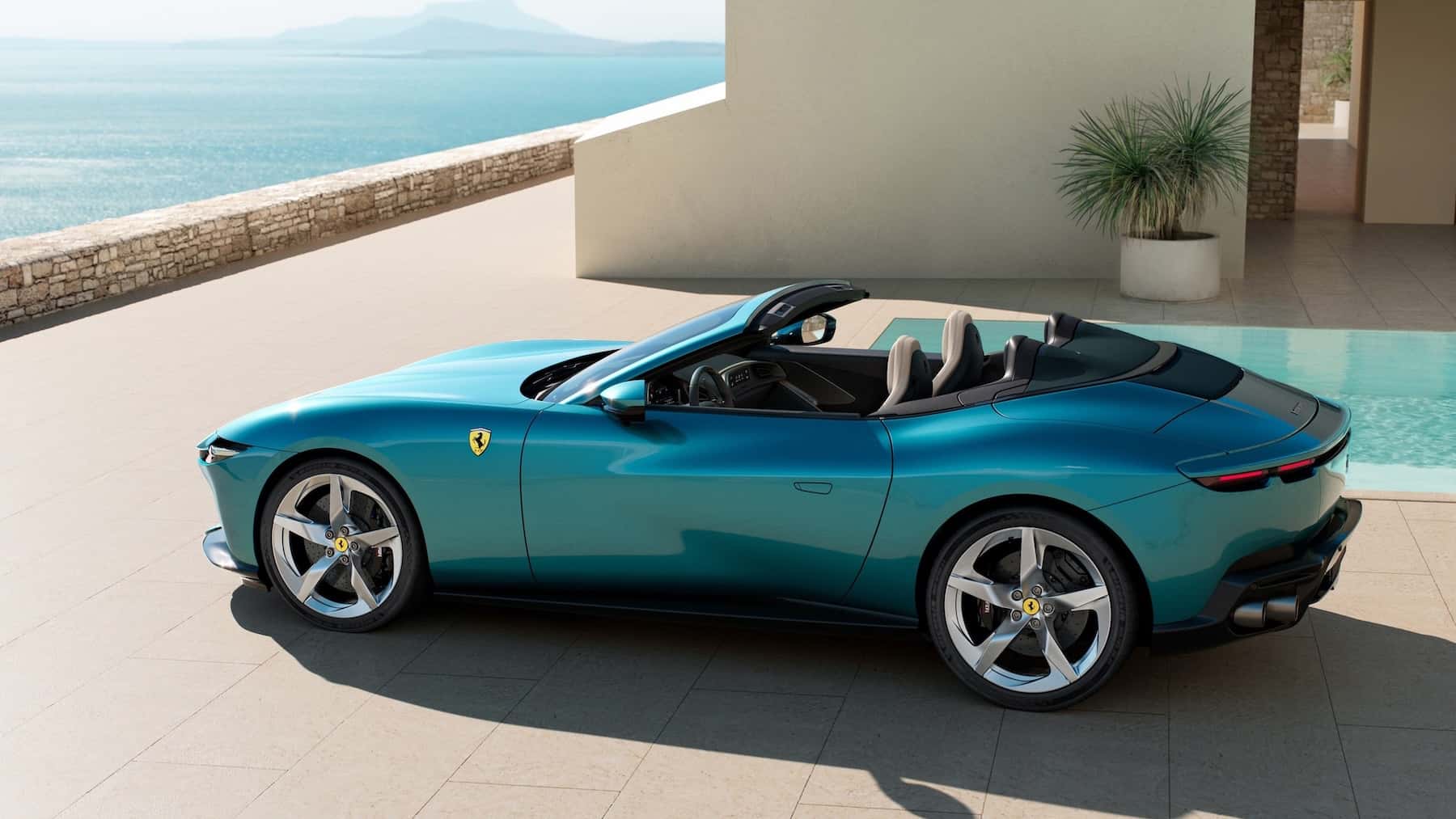 Blue Ferrari Amalfi Spider parked at a home by the ocean