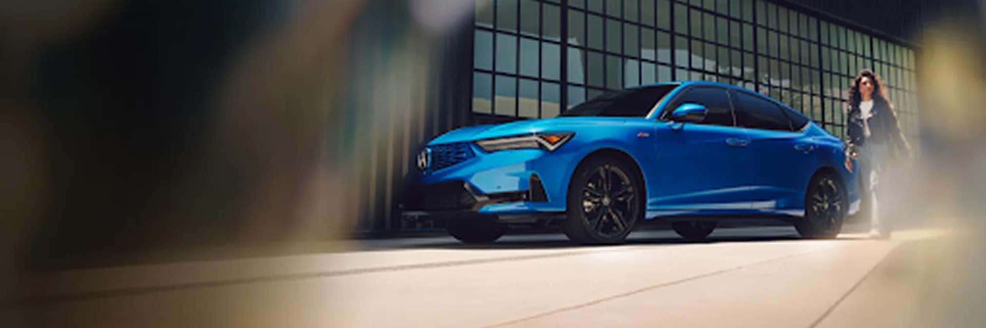 woman standing next to blue 2026 acura integra