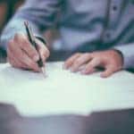 Persona firmando documentos para el financiamiento de un vehículo Acura.