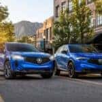 Two blue Acura SUVs parked side by side on a city street