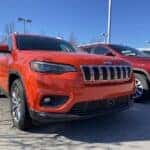 Front grille of red Jeep Cherokee on car dealership lot