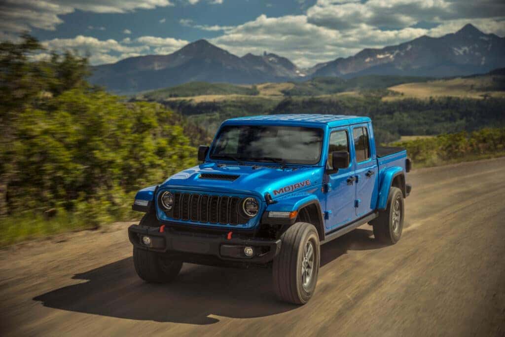 A blue Jeep Gladiator on the backroads in the mountains.
