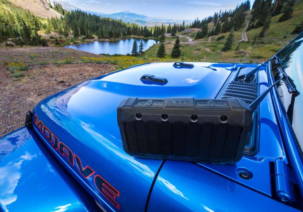 Bluetooth speaker on a blue Jeep Gladiator with mountains in the background.