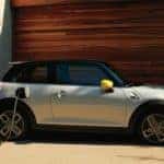 Young adult man walking to the passenger side of his MINI SE Electric Vehicle to charge.