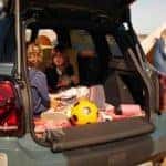 Kids sitting in the cargo area in a new 2021 MINI Countryman SAV while camping.