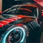 MINI Cooper inside of a building with lights reflecting off of the hood.
