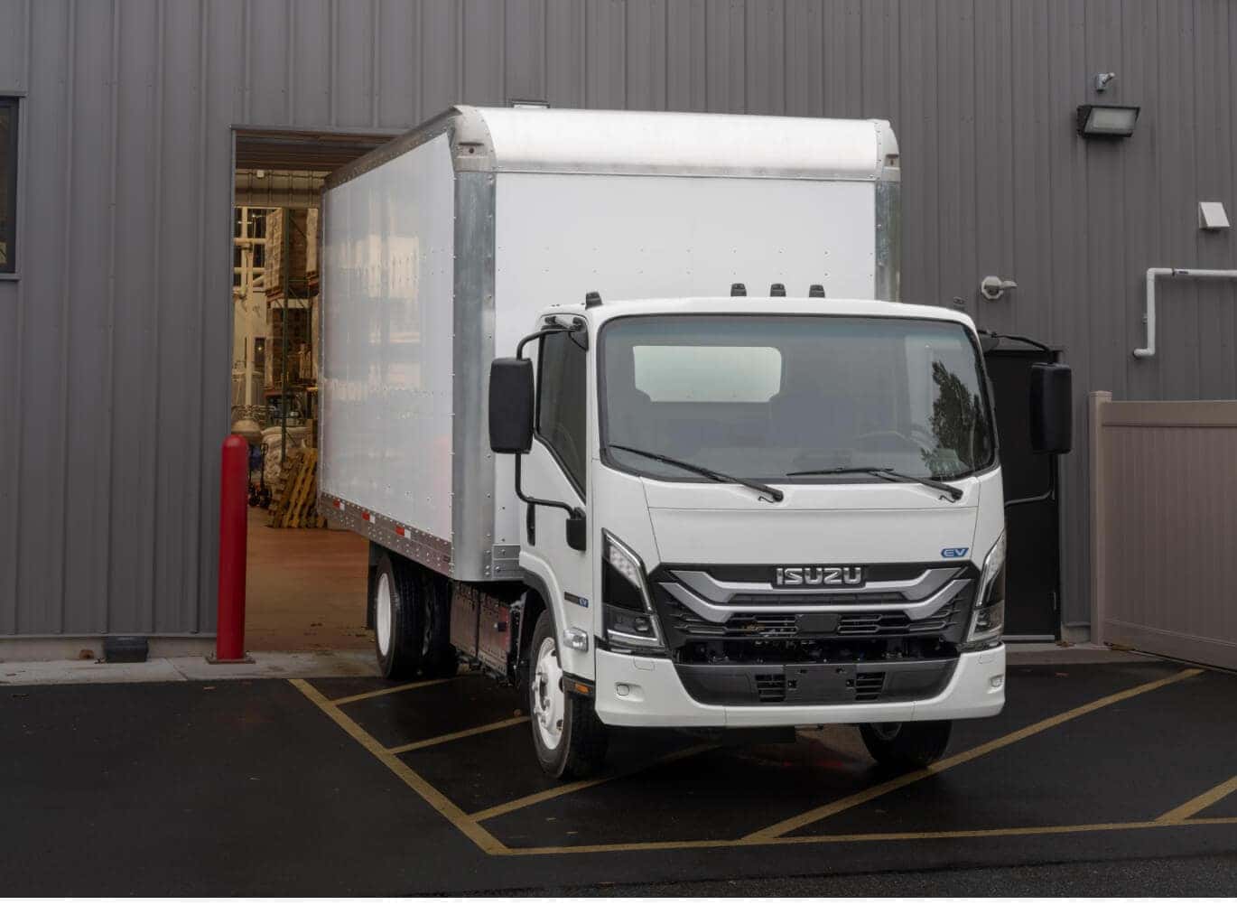 Isuzu NRR EV backed into a warehouse loading dock setting.