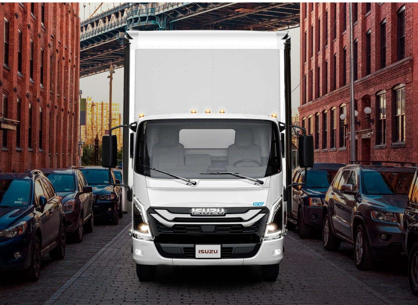 Isuzu NRR EV driving down a historic brick street framed by urban buildings.