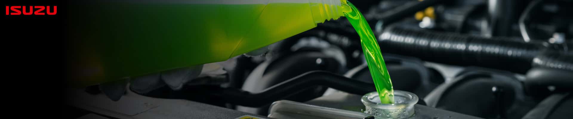A close-up of a gloved hand pouring green coolant into an open radiator with the Isuzu logo shown.