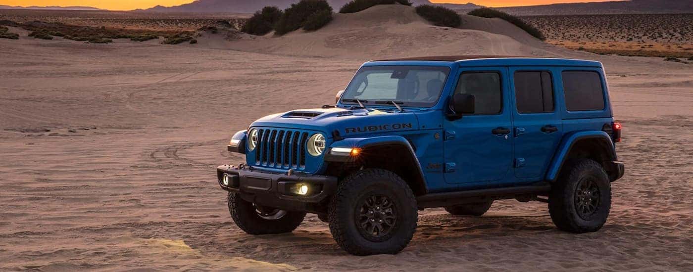 A blue 2021 Jeep Wrangler Rubicon is shown from the side parked in a desert.