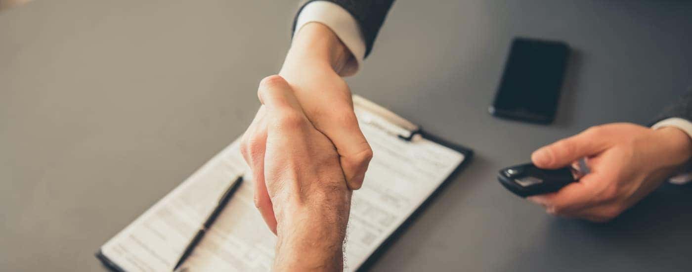 A salesperson is shaking hands with a customer at a Jeep dealership.