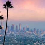 Seven palm trees in front of many tall Los Angeles buildings