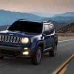 A blue 2019 Jeep Renegade drives on a quiet California mountain road