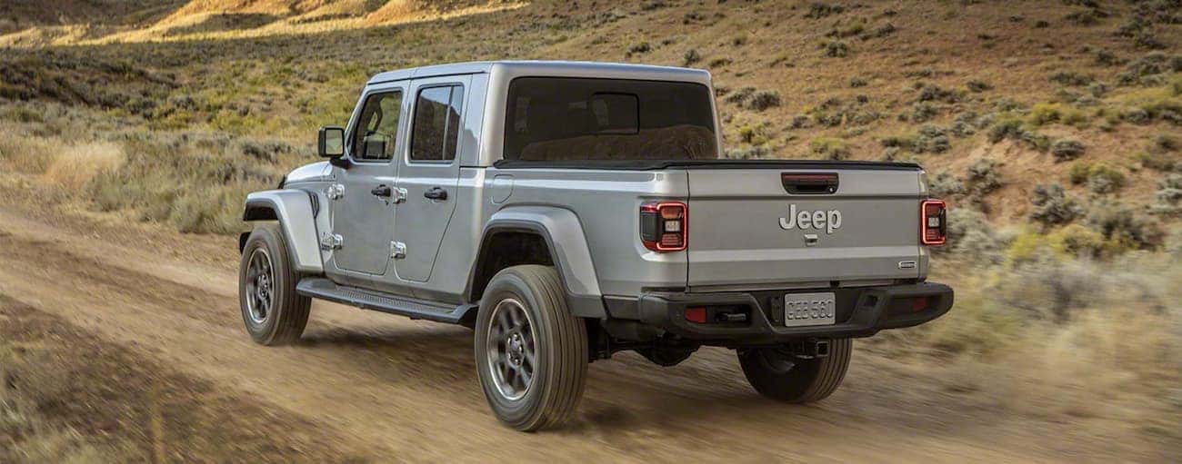 A grey 2020 Jeep Gladiator is driving on a dirt road outside Costa Mesa, CA.
