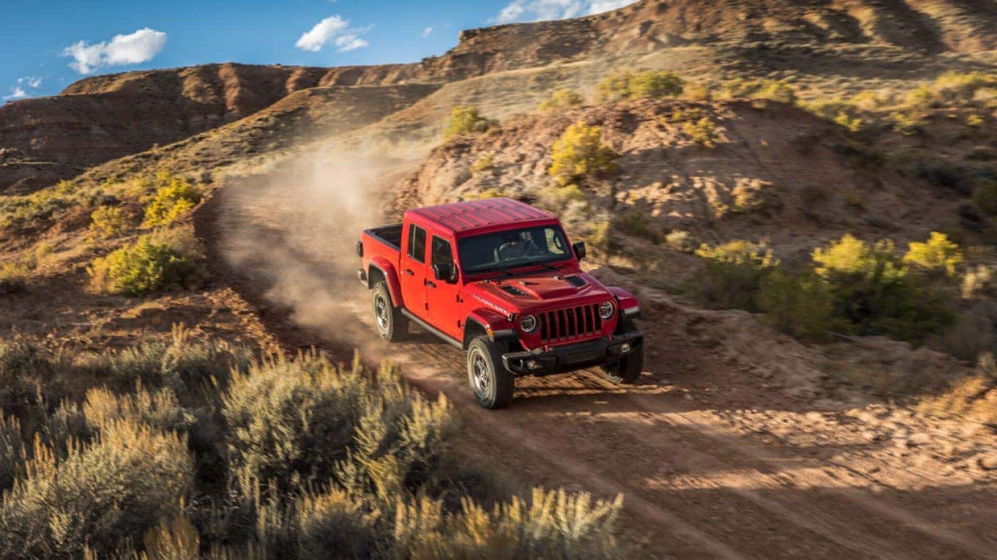 A red 2020 Jeep Gladiator driving on a mountain dirt road