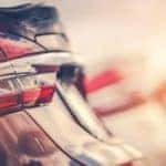 A closeup of the tailgates of used cars in a row with a sun glare.