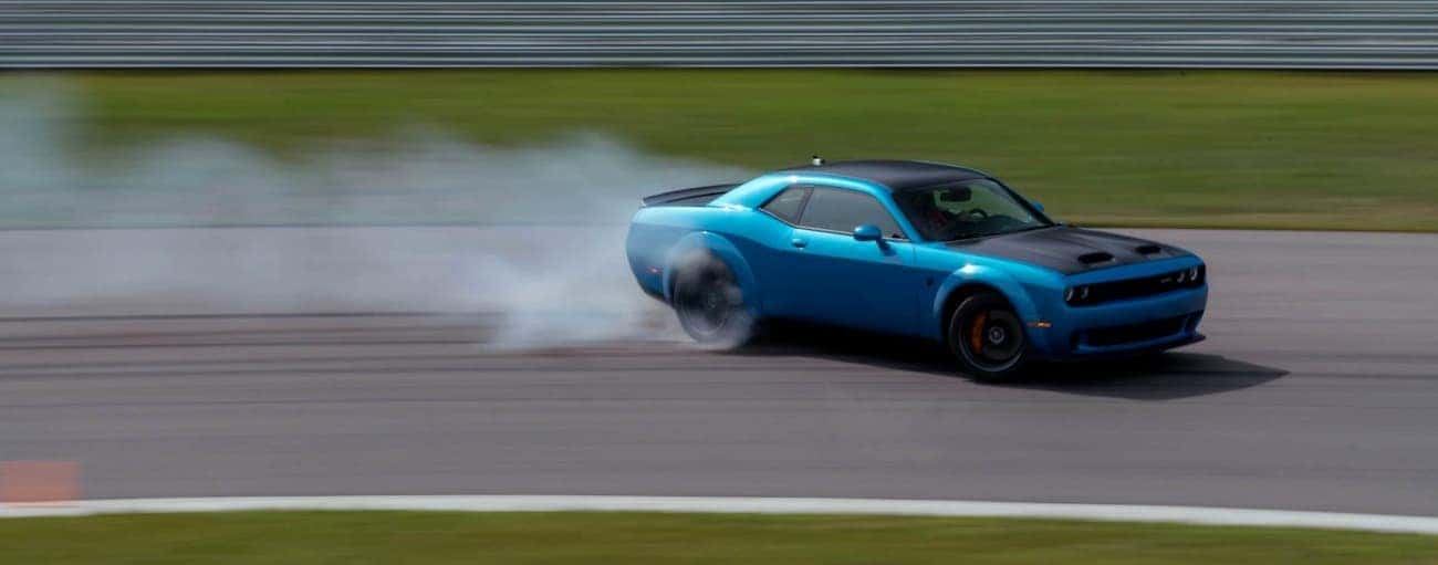A blue 2020 Dodge Challenger is drifting around a track near Costa Mesa, CA.