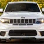 A white 2020 Jeep Grand Cherokee is facing forward while driving on a highway near Costa Mesa, CA.