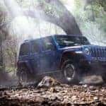 A blue 2020 Jeep Wrangler is off-roading in the woods near Costa Mesa, CA.