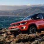 A red 2020 Jeep Compass Trailhawk is on a cliff at the ocean near Costa Mesa, CA.