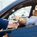 A smiling customer is taking the keys to his new to him used car.