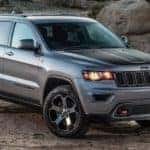 A grey 2017 jeep Grand Cherokee is driving on a dirt trail near Costa Mesa, CA.